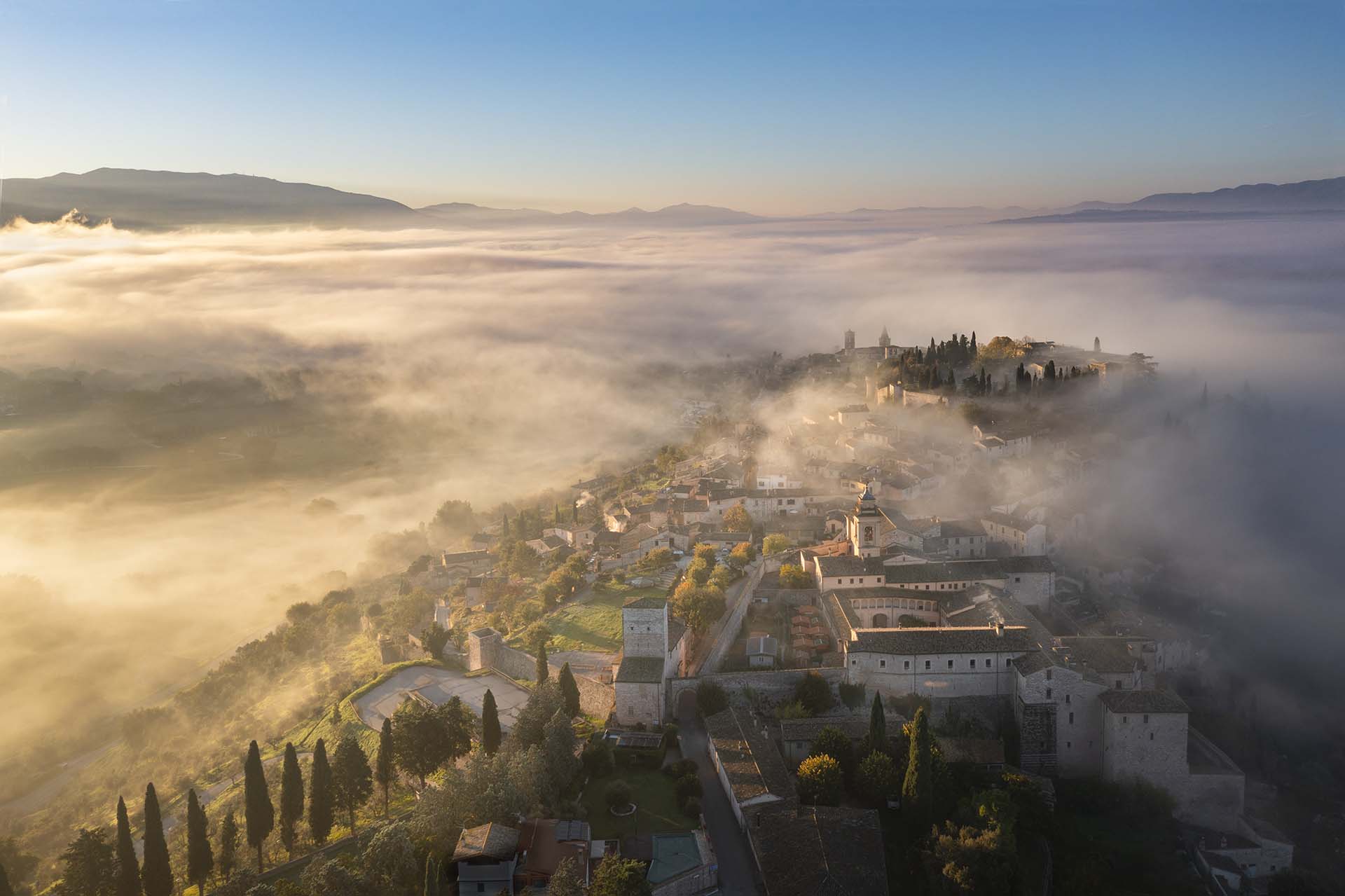 L'antico borgo medievale di Spello accarezzato dalla nebbia mattutina.