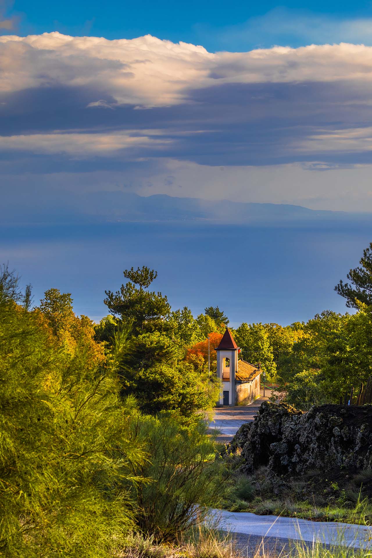 Etna, la chiesetta del Magazzeni tra i boschi di Sant'Alfio, sullo sfondo la Calabria e lo Stretto