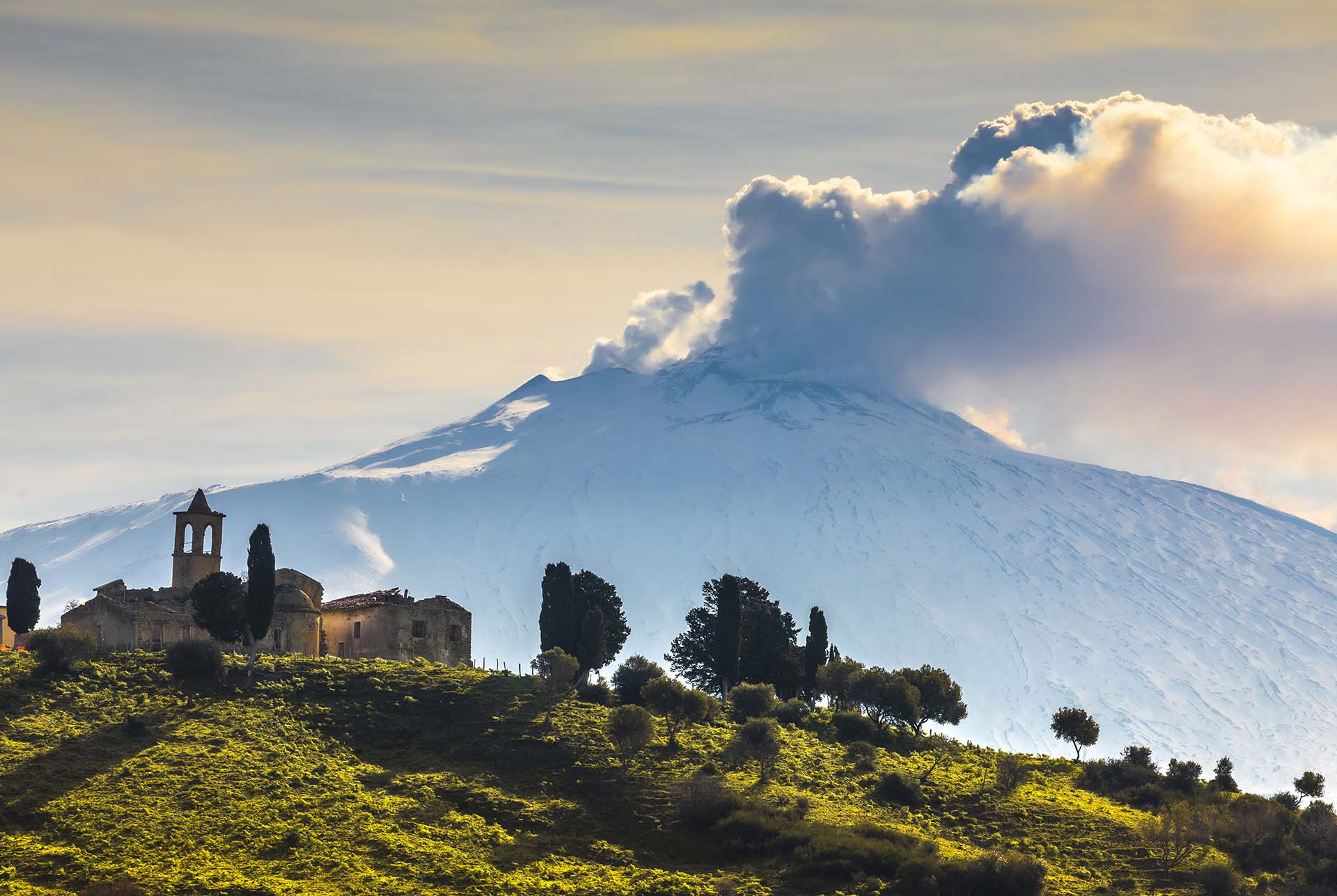 Borgo Giuliano incorniciato dall'Etna vestita di bianco e fumo