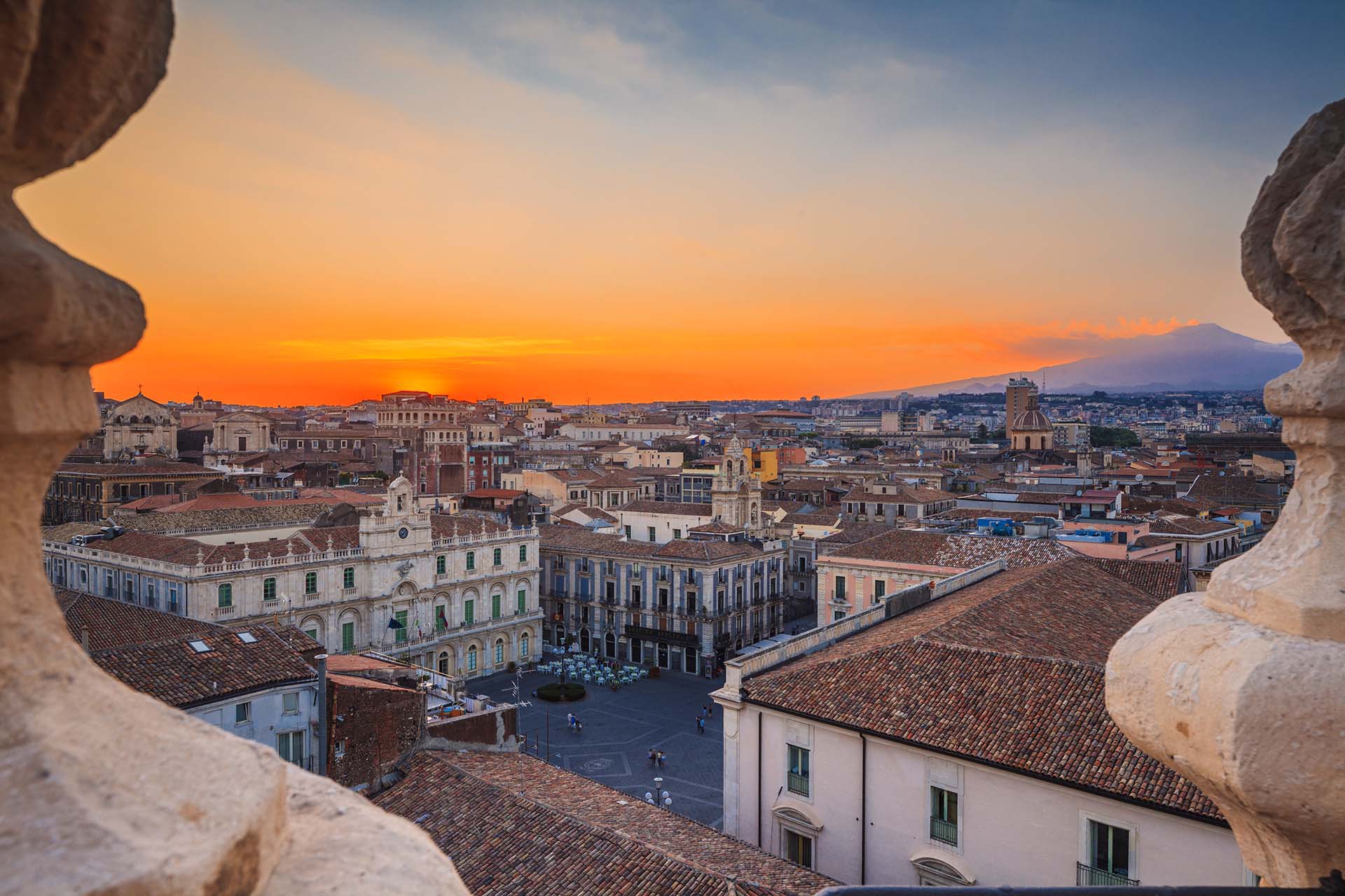 Catania Piazza Università, un Tetto di Storia al Crepuscolo con la Maestosità dell'Etna