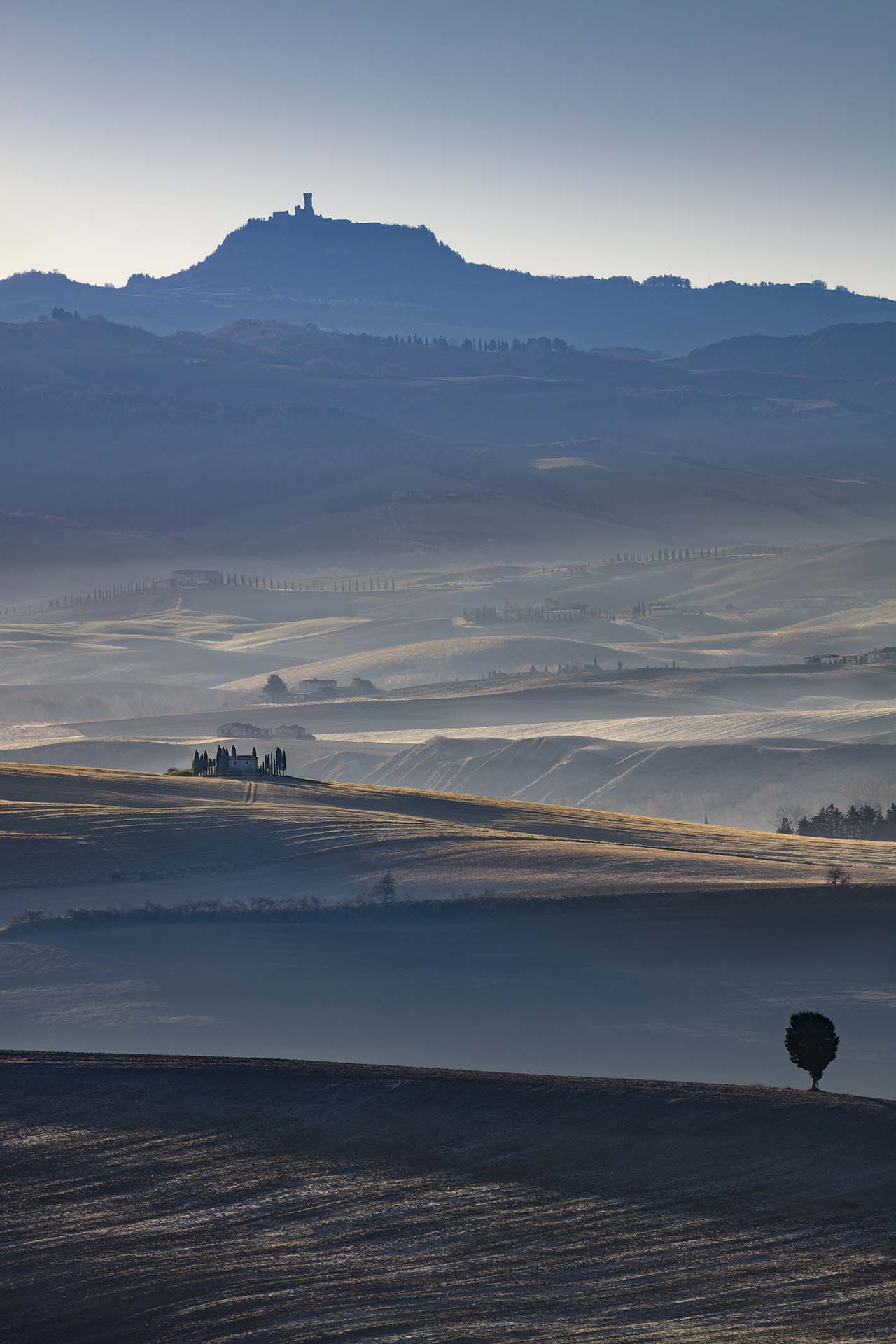 Le sinuose colline della Val d'Orcia e sullo sfondo il Castello di Radicofani.