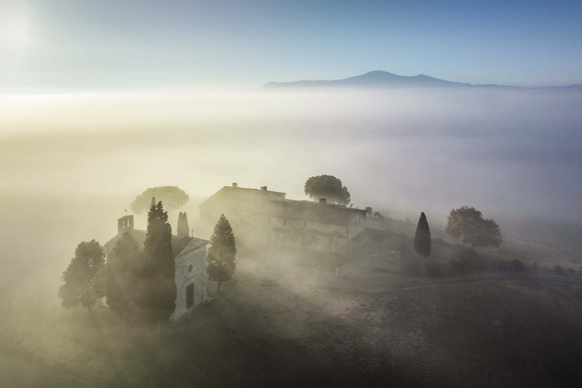 La Cappella della Madonna di Vitaleta tra la nebbia e il Monte Amiata.