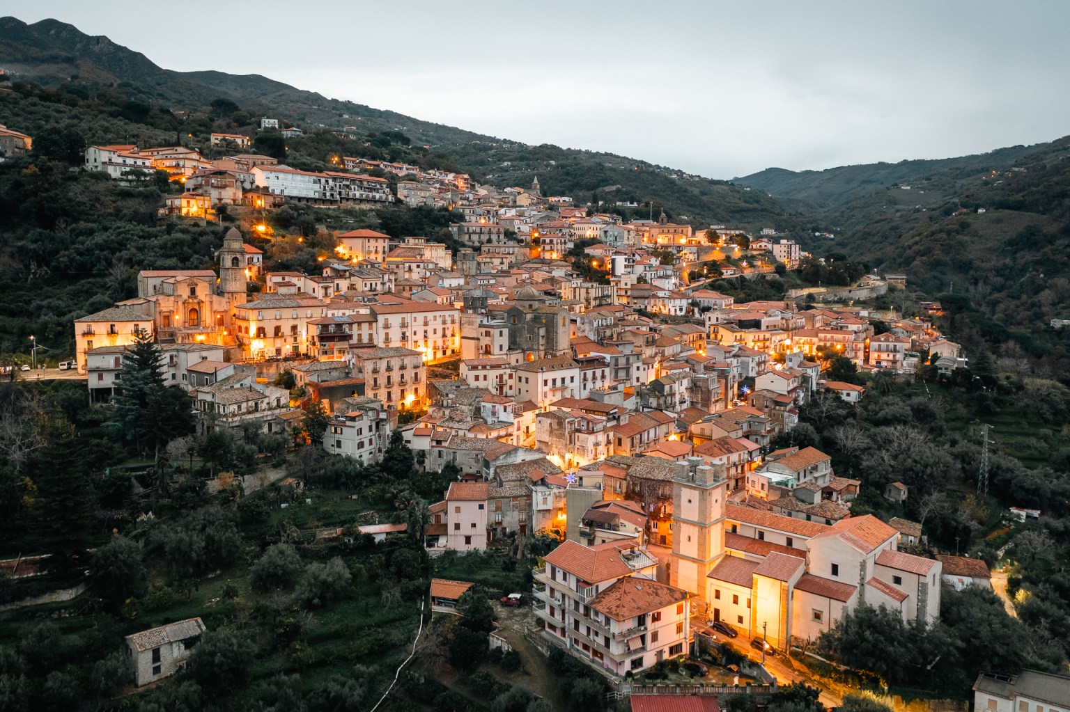 Veduta del centro storico di Sant’Angelo di Brolo illuminato dalle luci serali, fotografato al tramonto.