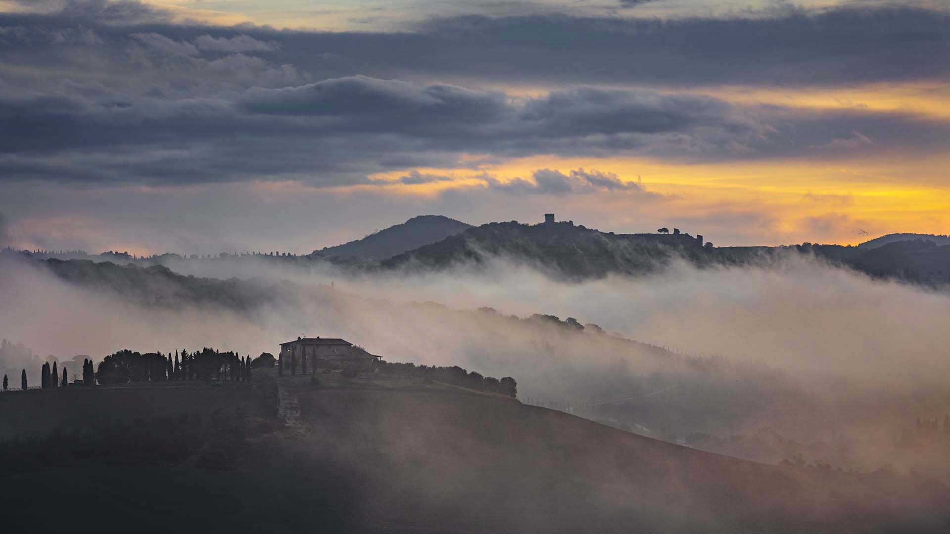 Paesaggio della val d'Orcia con il borgo fortificato di Monticchiello sullo sfondo.