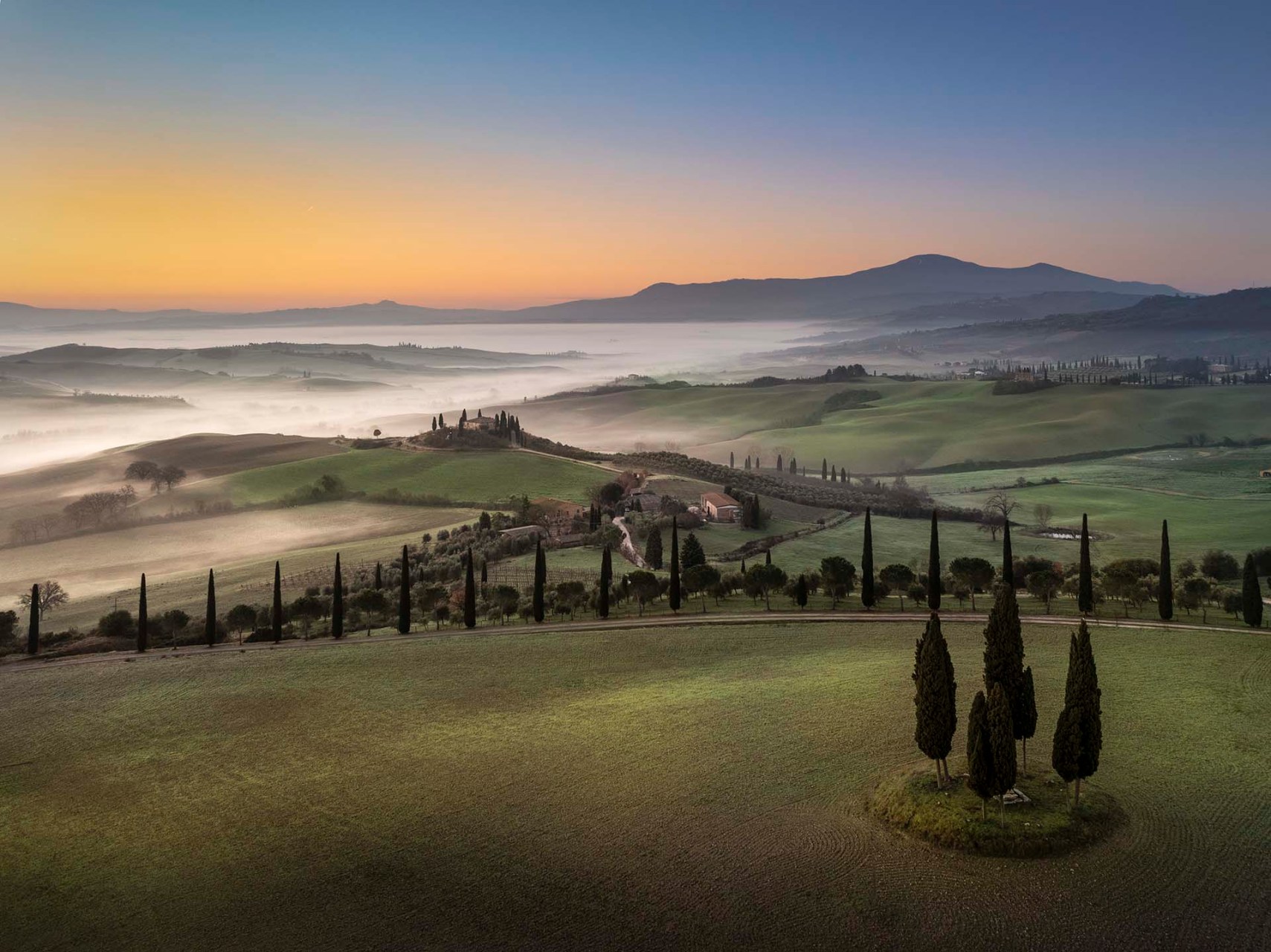 Il paesaggio della Val d'Orcia tra nebbie, cipressi e il Monte Amiata.