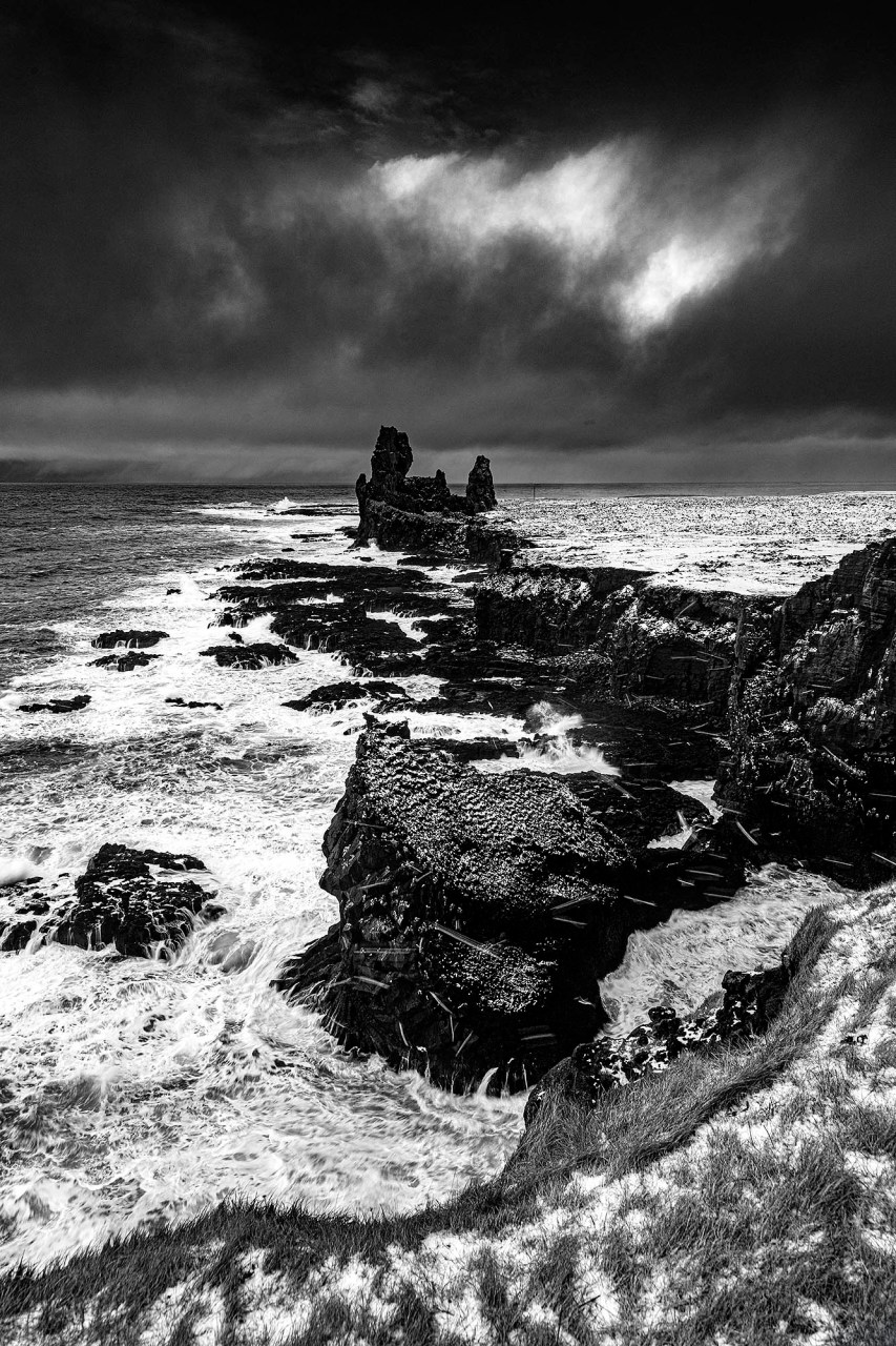 Fotografia professionale in bianco e nero dei Lóndrangar in Islanda, picchi vulcanici di basalto sulla costa di Snæfellsnes durante l'inverno.