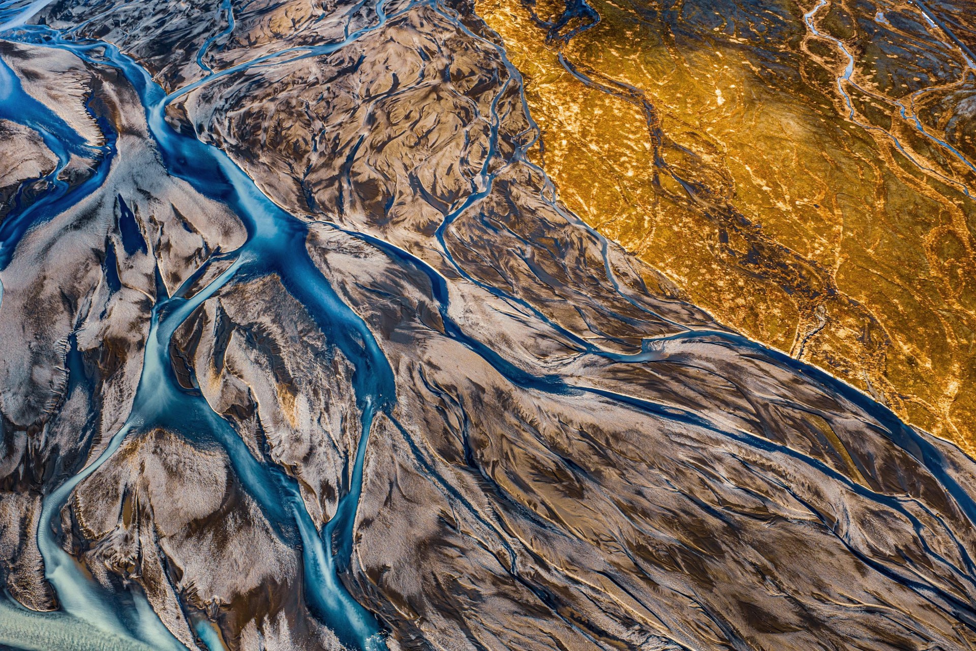 Veduta aerea dei fiumi glaciali in Islanda, labirinti d'acqua azzurra e sedimenti minerali arancioni sulla cenere vulcanica