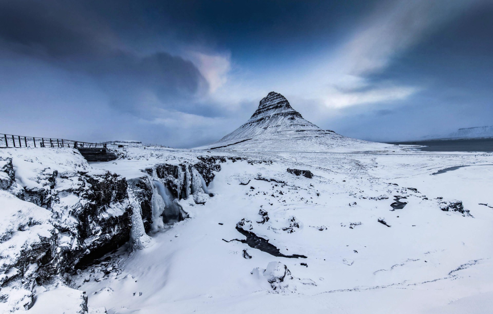 Veduta invernale del monte Kirkjufell e della cascata Kirkjufellsfoss ghiacciata in Islanda. Fotografia professionale di paesaggio artico firmata 101-zone.com