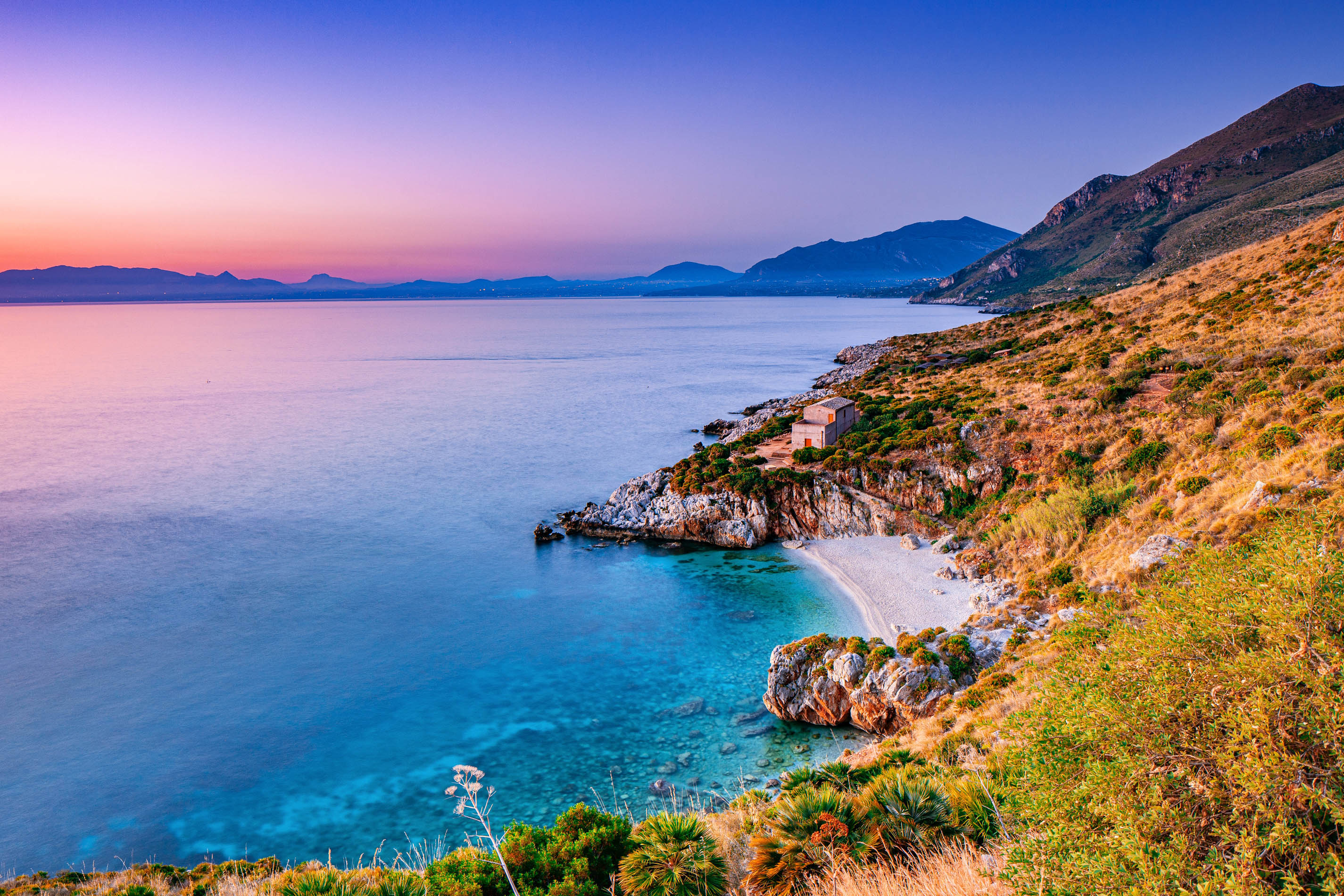Veduta panoramica di Cala Tonnarella dell'Uzzo nella Riserva dello Zingaro, San Vito Lo Capo, all'ora d'oro. Acque turchesi e macchia mediterranea