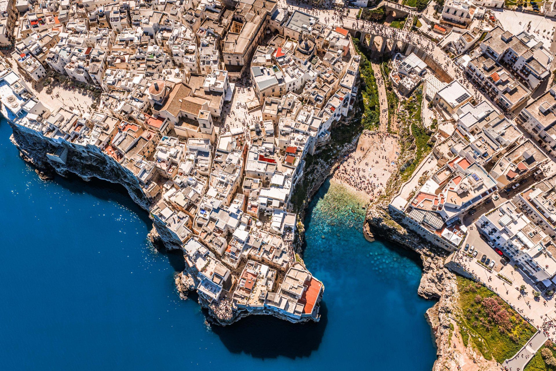 Veduta aerea di Polignano a Mare tra roccia e mare blu.