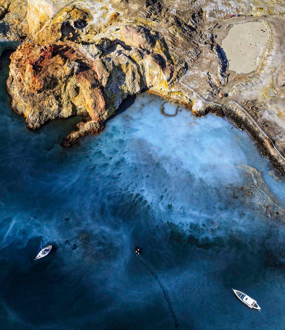 Fotografia aerea zenitale delle acque calde e dei fanghi di Vulcano nelle Isole Eolie con barche ormeggiate nel mare blu, servizio fotografico d'autore di Nino Bartuccio