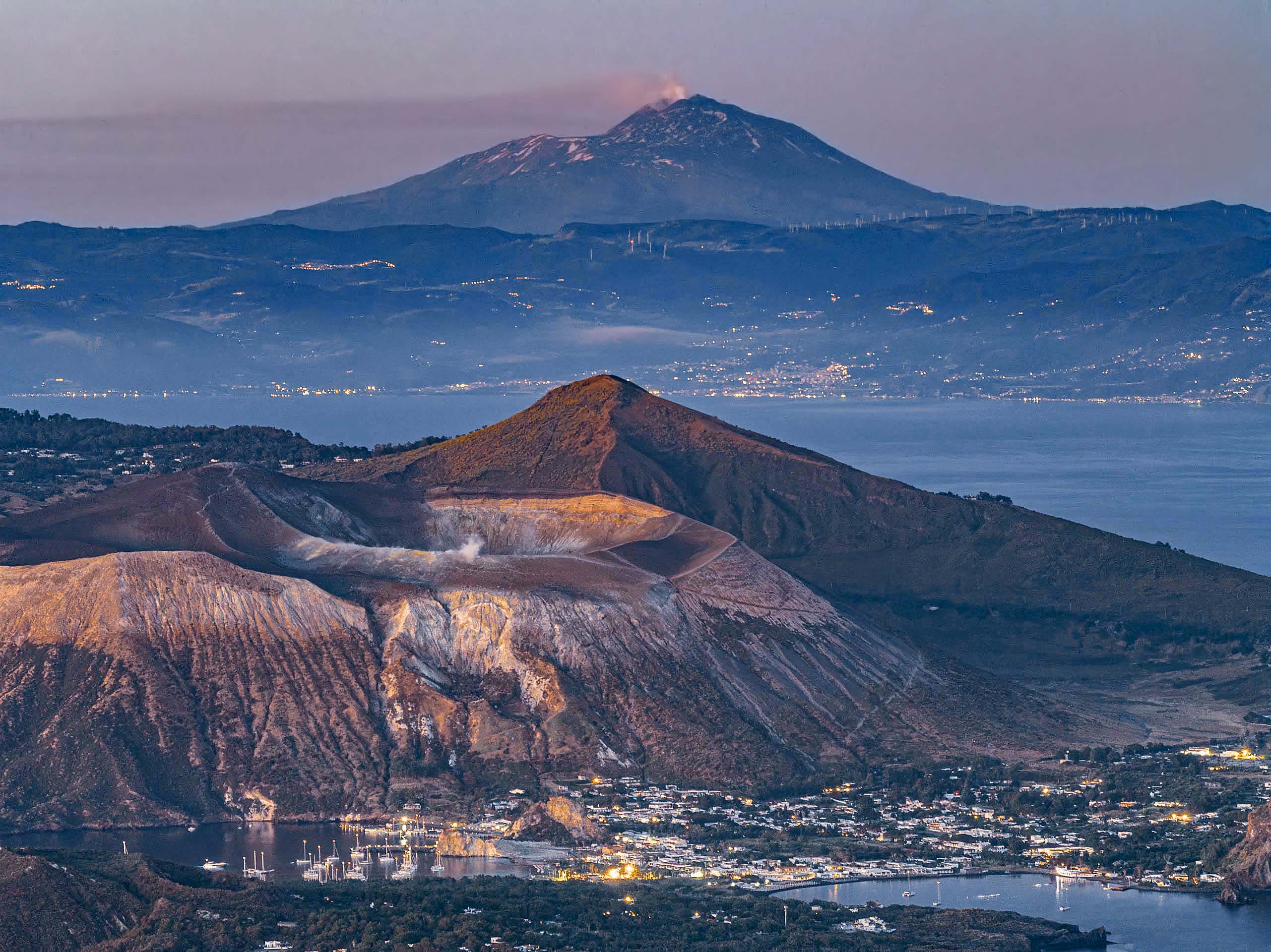 Cratere dell'isola di Vulcano con fumi sulfurei e il Monte Etna sullo sfondo della costa siciliana foto nino bartuccio,