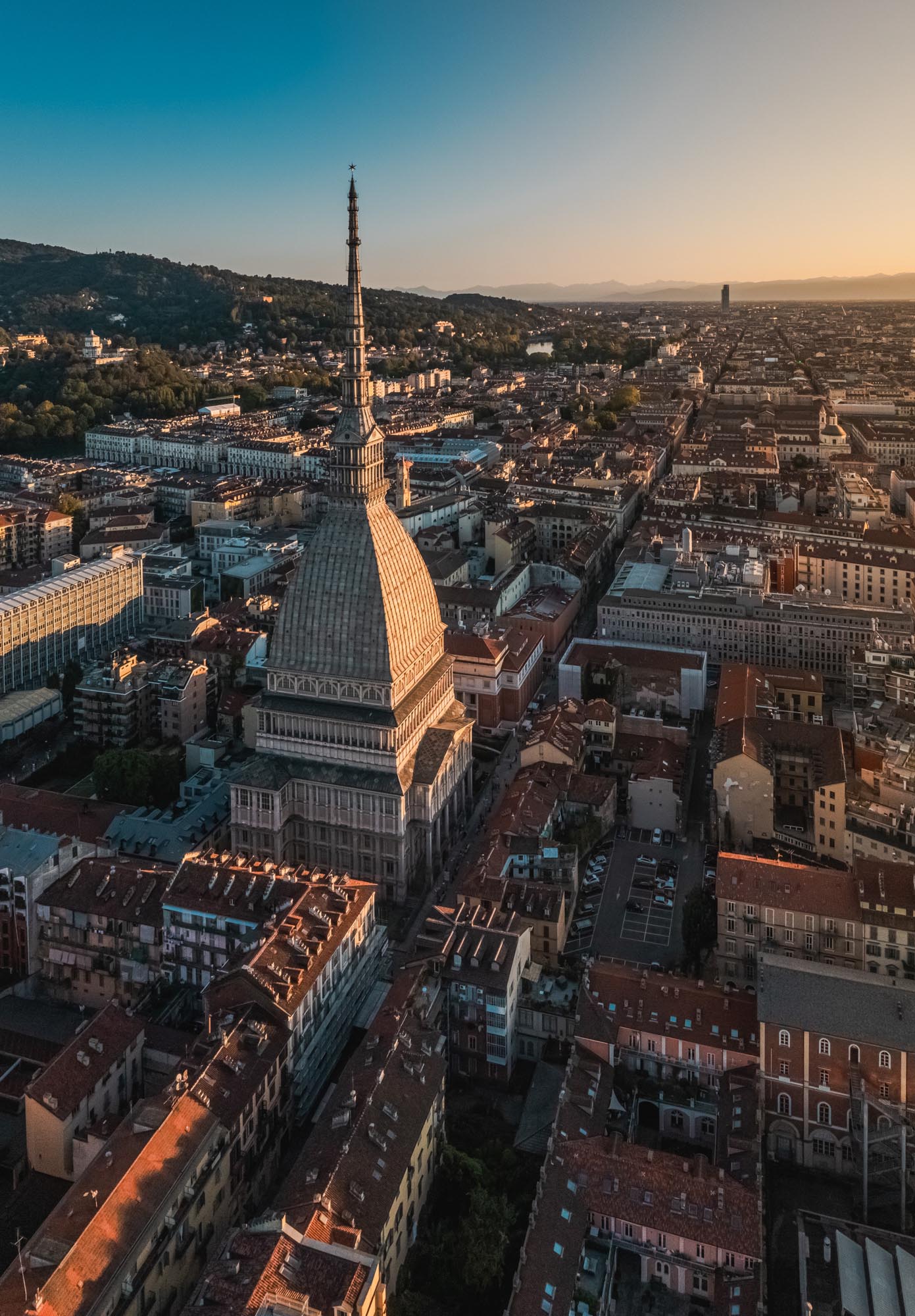Veduta aerea della Mole Antonelliana a Torino durante il tramonto, con i tetti della città illuminati dalla luce calda © Filippo Barbaria 2023
