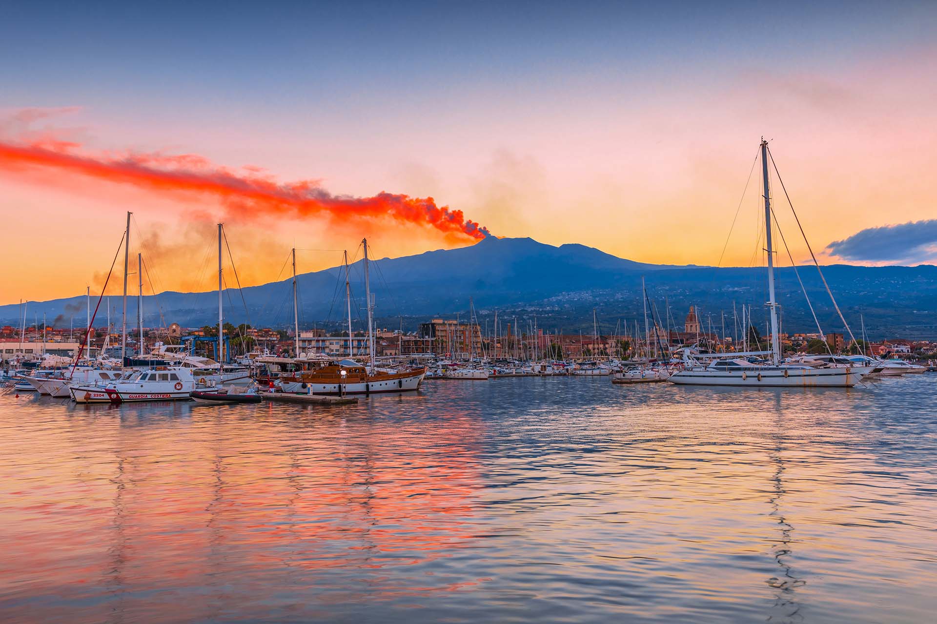 SIM-1082939 - Il Porto dell'Etna a Riposto dominato dal vulcano in eruzione al tramonto