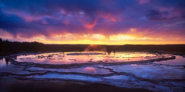 Great Fountain Geyser circondato dalle sue caratteristiche pozze d'acqua terrazzate durante un tramonto colorato nel Parco Nazionale di Yellowstone