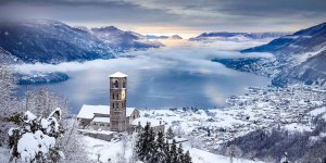 Panorama del Lago di Como con la chiesa di Sant'Eusebio a Peglio dopo una bellissima nevicata.