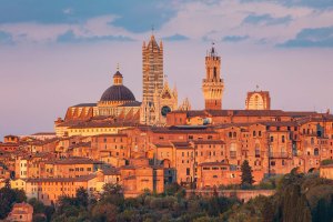 Tramonto rosso sul centro storico di Siena con vista su Duomo e Torre del Mangia.