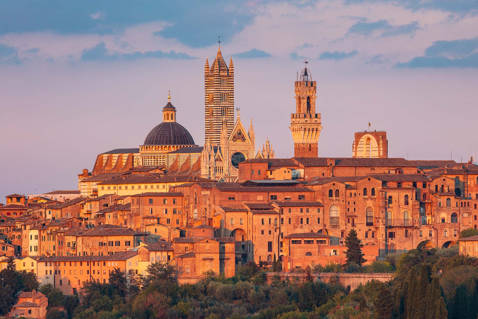 Tramonto rosso sul centro storico di Siena con vista su Duomo e Torre del Mangia.