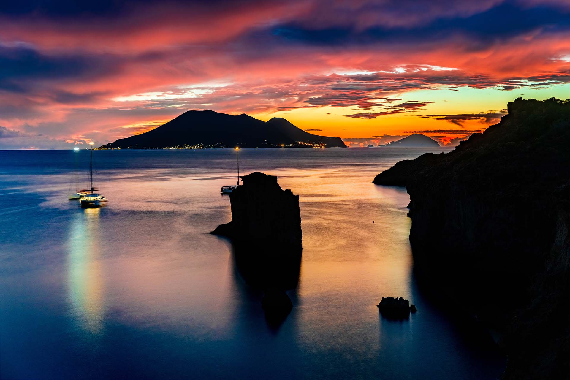 Panarea, luci e riflessi al crepuscolo sullo Scoglio Brigantino a Cala Junco, con vista su Salina e Filicudi