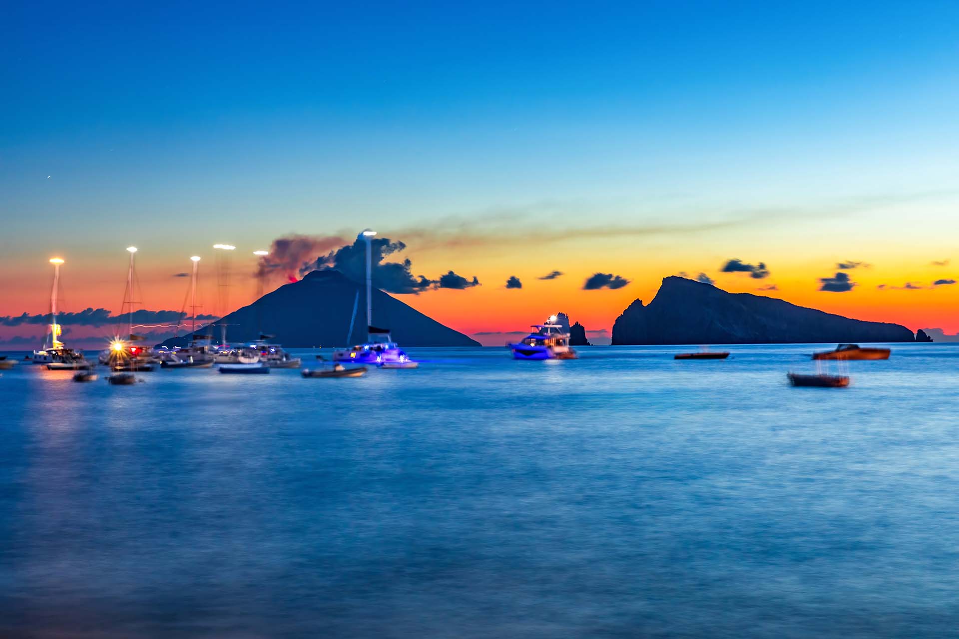 Nel mare di Panarea, barche e yacht all’ancora tra il profilo di Basiluzzo e lo Stromboli incandescente