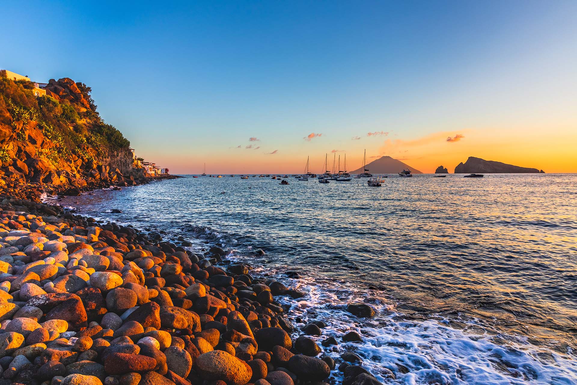 SAFF1800 - Alba dorata sui ciottoli della spiaggetta del porto di Panarea con vista sulle isole di Basiluzzo e Stromboli